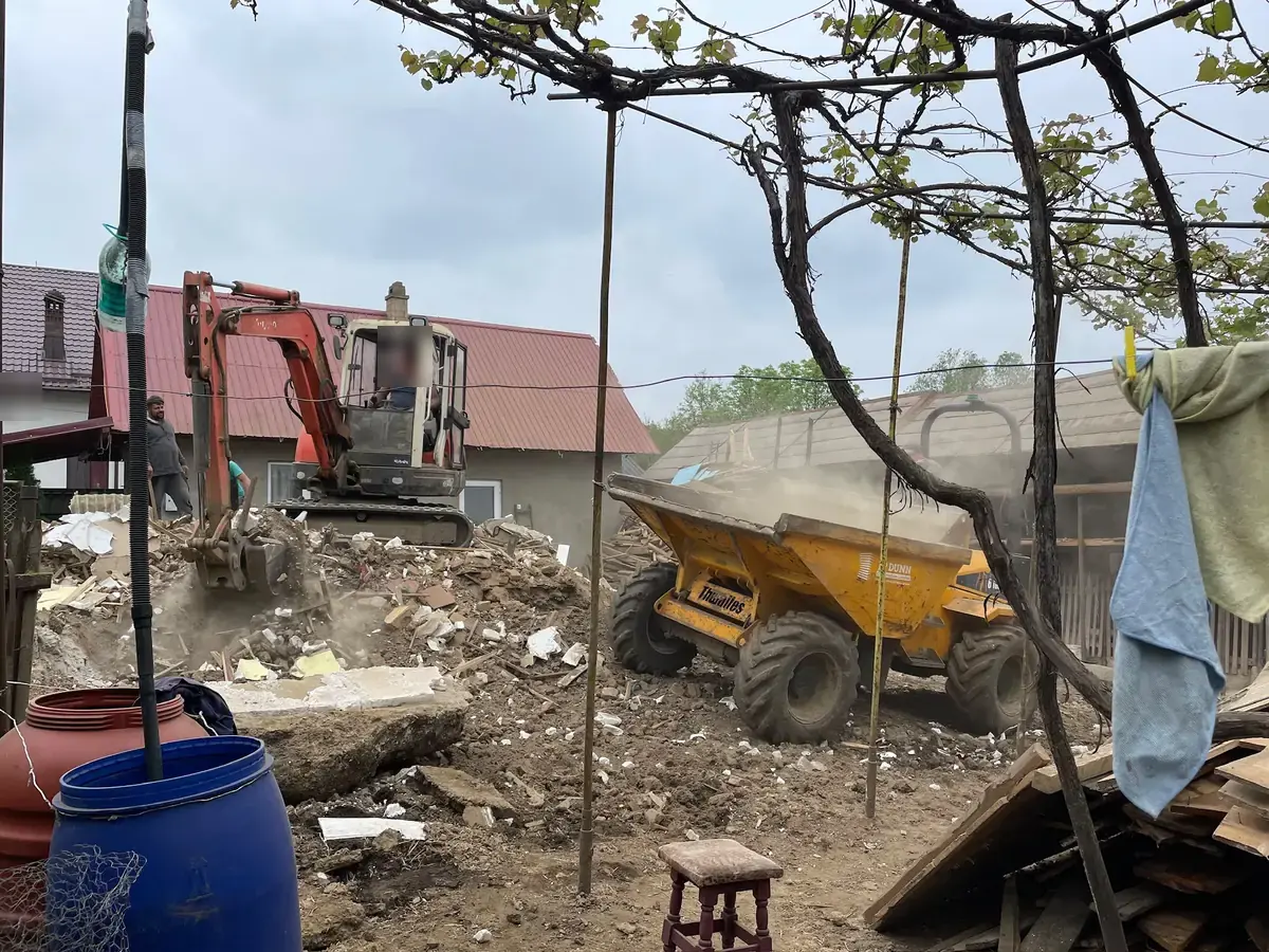 Excavatorul încarcă molozul rămas după demolarea unei case
