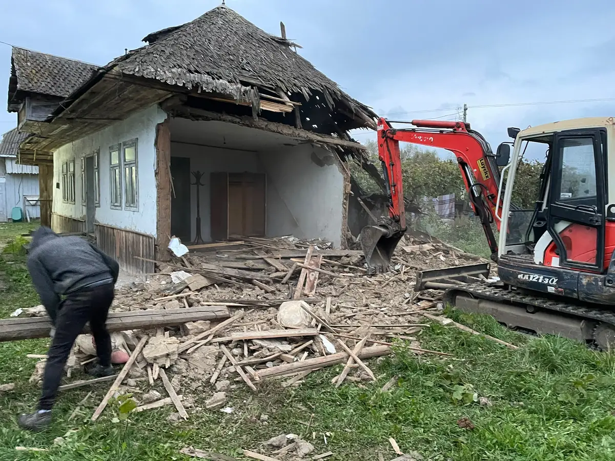 Excavator dărâmând controlat zidurile unei case vechi de cărămidă